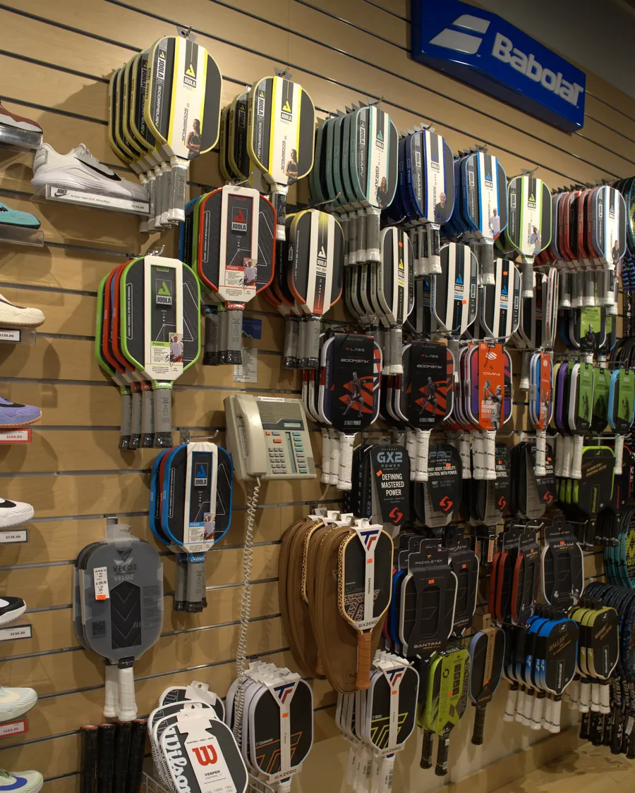 Pickleball paddles from Joola, Paddletek and Wilson on the wall at the Mequon shop.