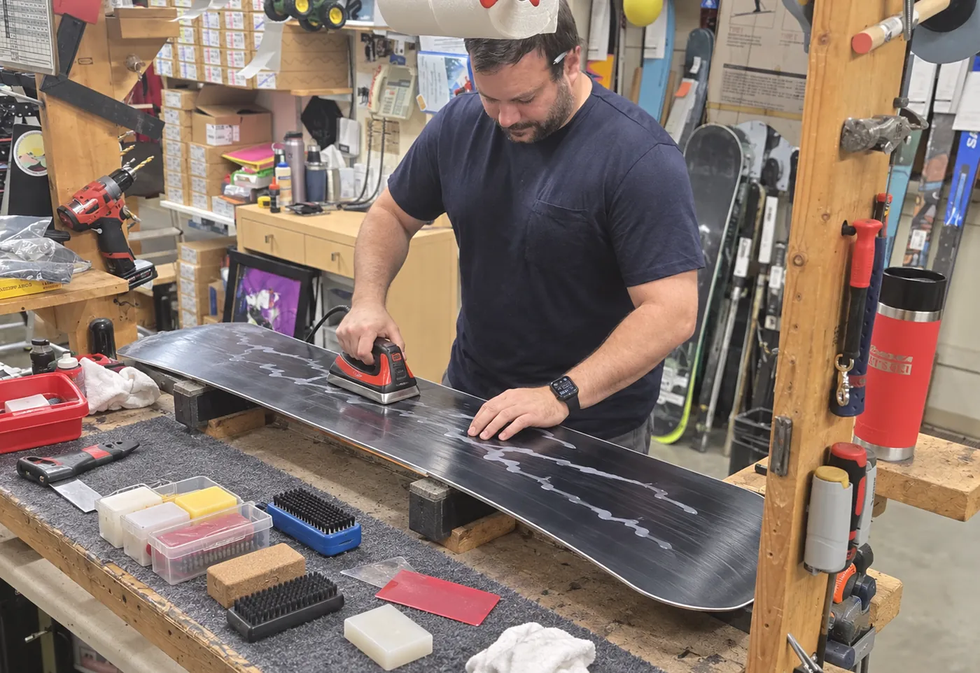A technician hot-waxing a snowboard at the service bench in the Mequon shop.